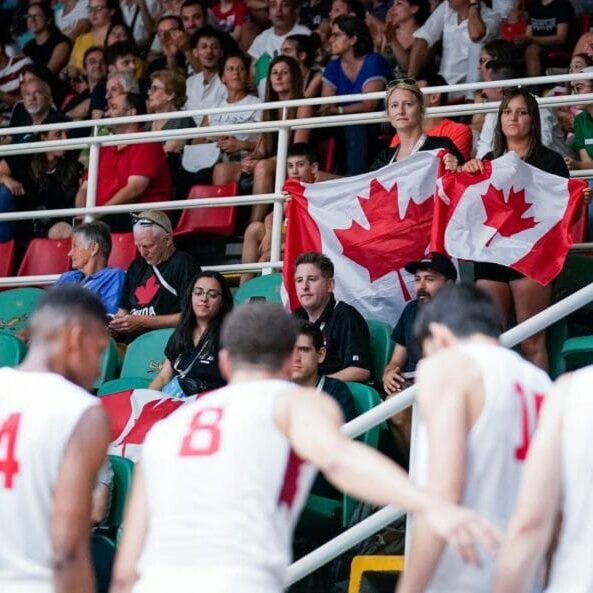 In this image: Two members from the crowd hold Canada flags.
