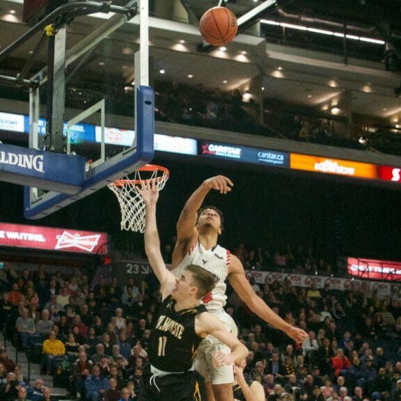 In this image: Keevan Veinot's shot is blocked by Eddie Ekiyor.