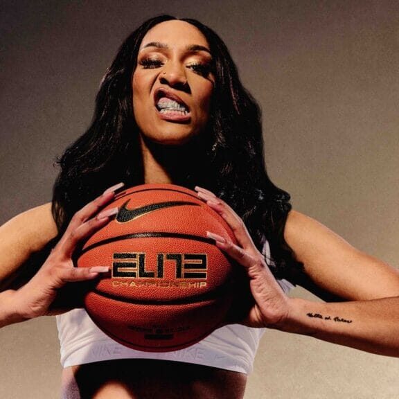 A’ja Wilson stands grasping a basketball between her hands while having a grill in her mouth. Photo by Amber Pinkerton. 