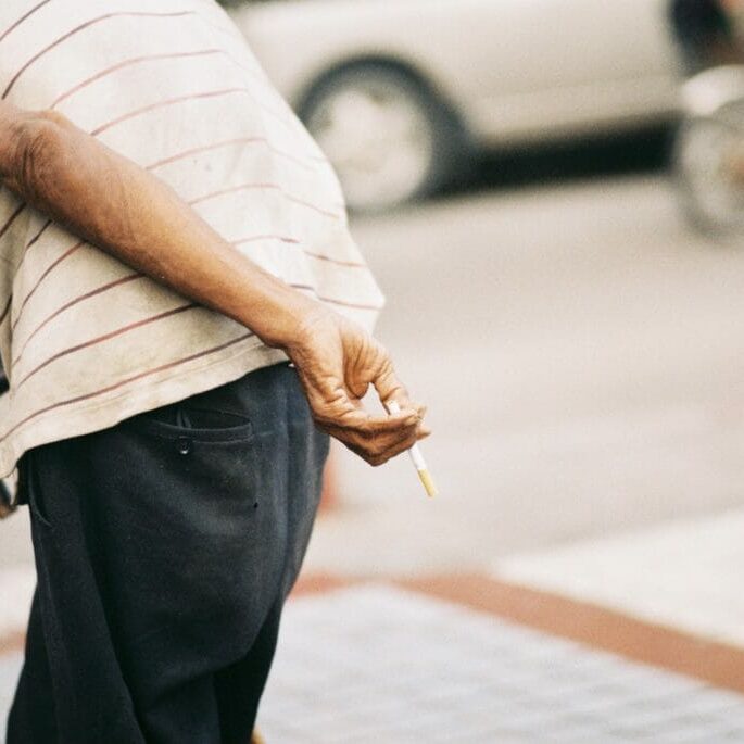 tilt-shift lens photography of man holding cigarette during daytime