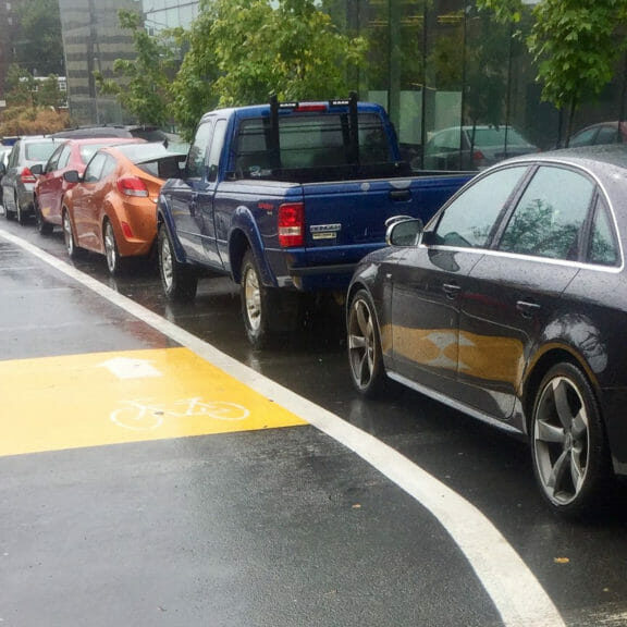 A bikelane with cars parked beside it.