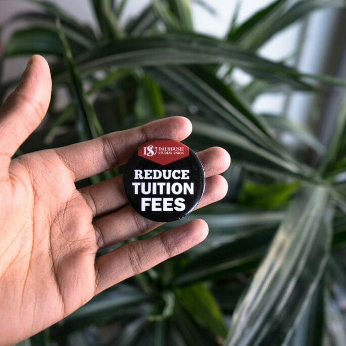 YourBill_EvanDeSilva In this image: Someone holding a "Reduce tuition fees" DSU pin.