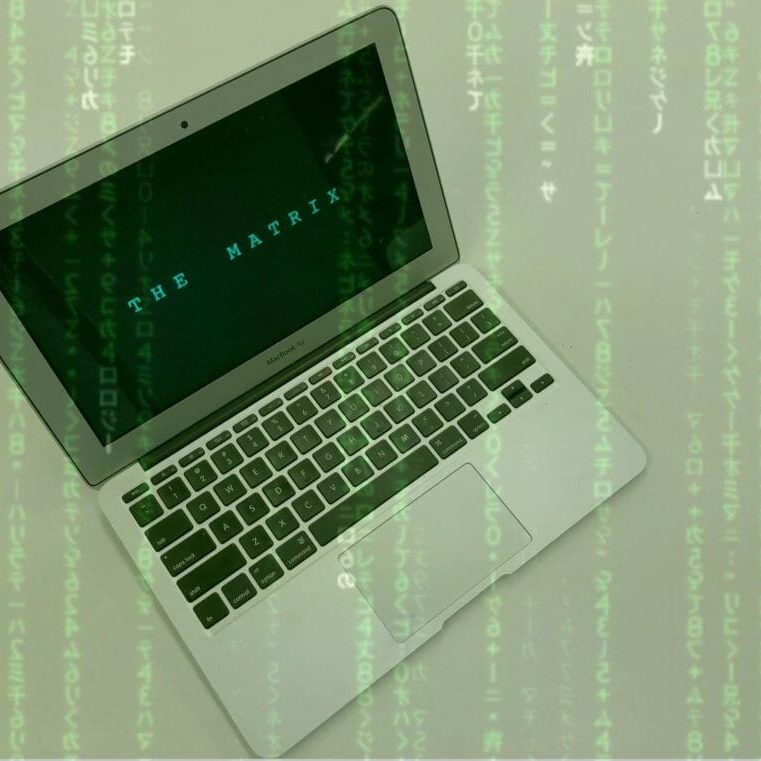 In this image: A laptop with The Matrix title screen and code running across the image.
