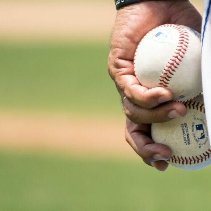 In this image: hand holding baseballs