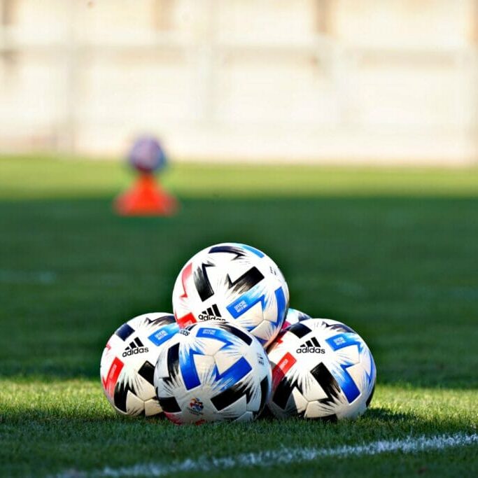 In this image: soccer balls on field